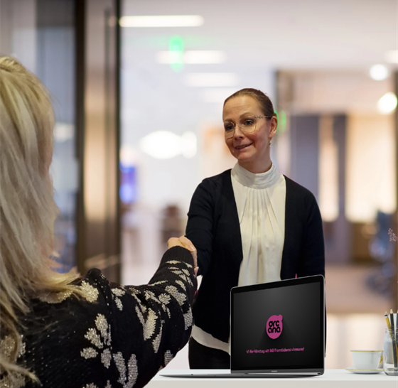 Kvinna hälsa på en annan kvinna som står bakom ett skrivbord